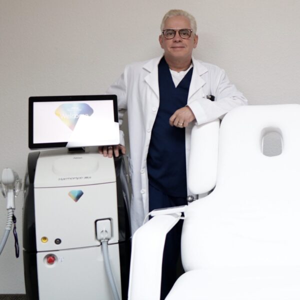Dr Roger Estevez medical director at Estevez Aesthetics standing in clinic beside advanced aesthetic laser equipment in Las Vegas NV
