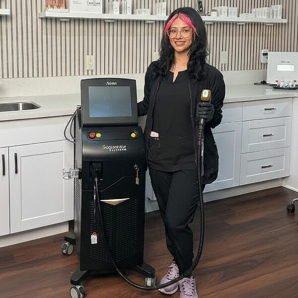 Ruby Mendez licensed aesthetician at Estevez Aesthetics standing in clinic with advanced aesthetic laser device in Las Vegas NV