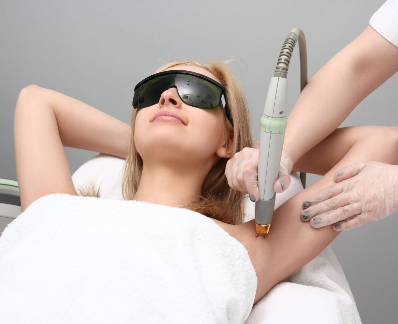 Laser hair removal of the armpits close-up, the girl lies in the cosmetologist's office in protective glasses from the laser irradiation smiles, the doctor removes the hair with a laser | Estevez Aesthetics in Las Vegas, NV